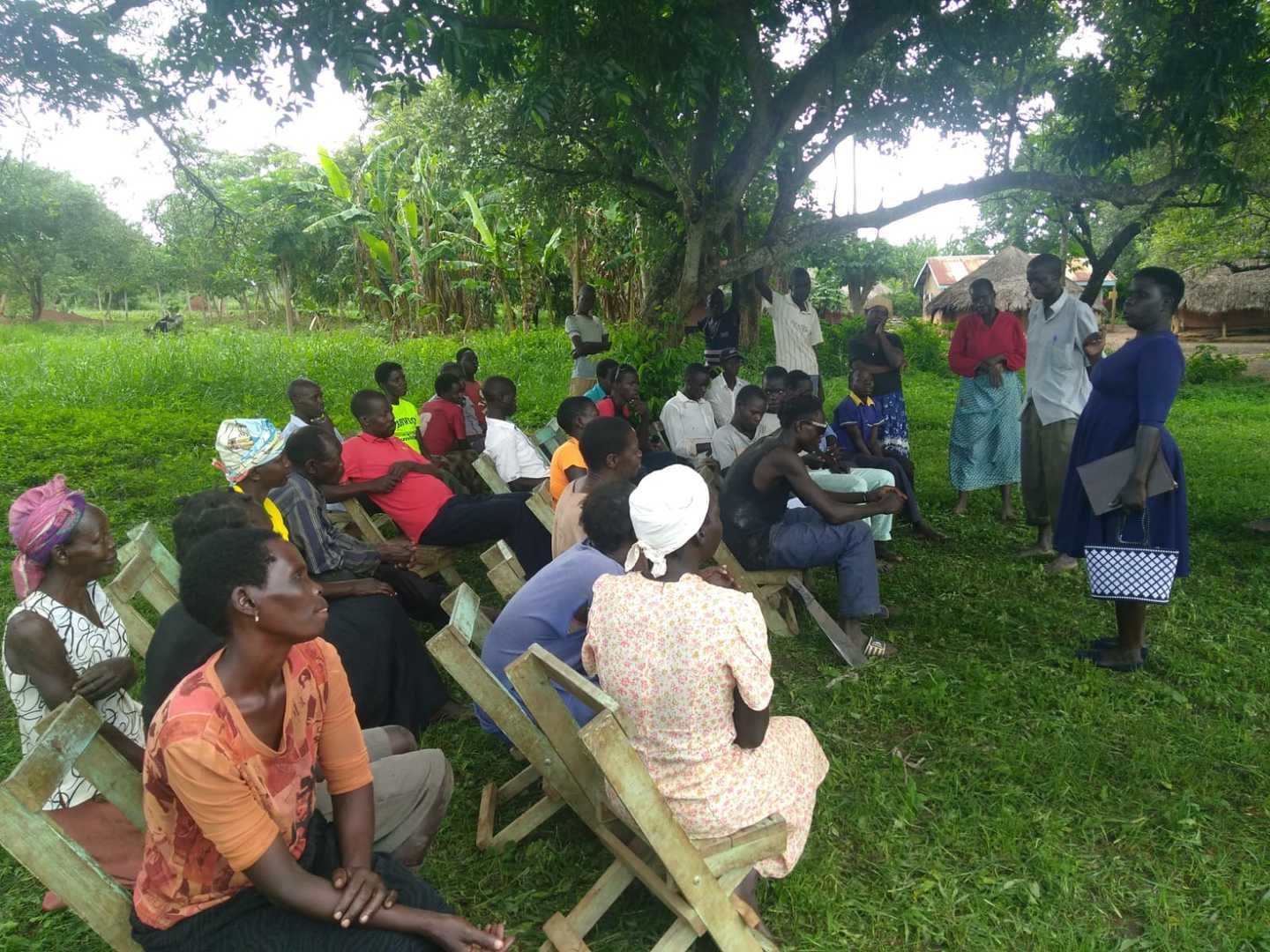 Archways, lira akullo in blue purple dress speaking to beekeeper group